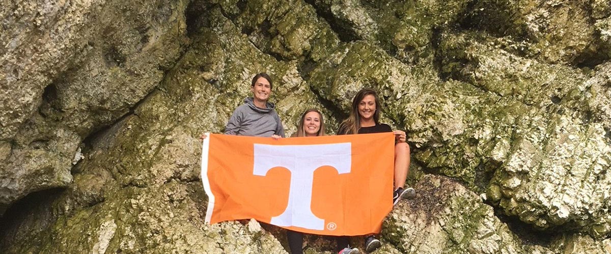 Students with UT flag at the mouth of a cave